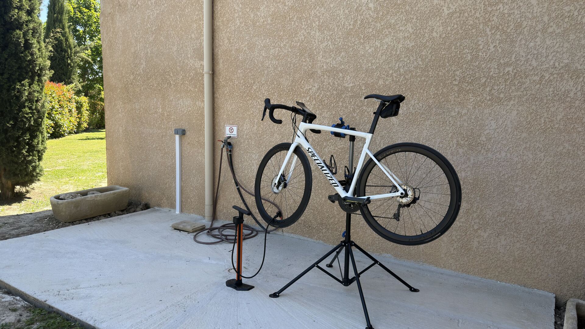 Zone vélo de l'Hôtel La Perna — pied d'atelier, pompe et point d'eau pour nettoyage